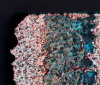 An unknown object with a rough surface made of small pyramids. Colours and shapes remind of an aerial image of a desert or an alien planet.